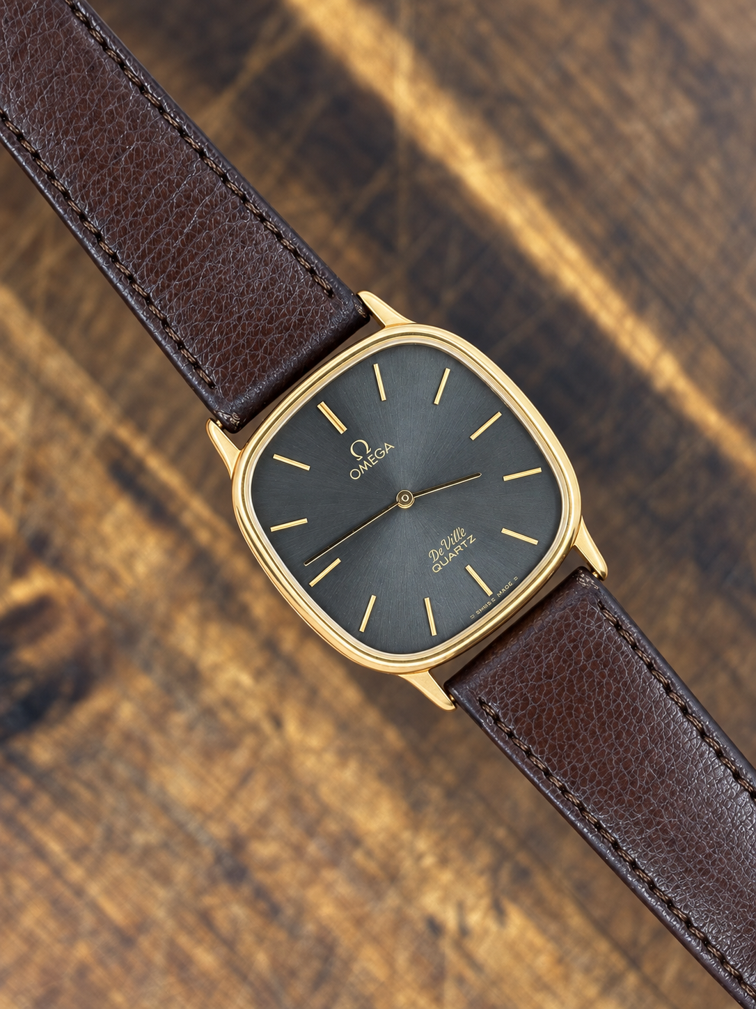 Vintage Omega De Ville Quartz watch with gold-tone cushion case, grey sunburst dial and brown leather strap